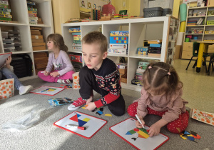 Dzieci układają według wzoru i własnego pomysłu obrazki z magnetycznych figur.