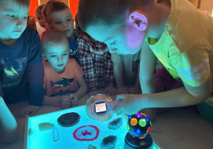 Dzieci obserwują przez lupę kryształy.