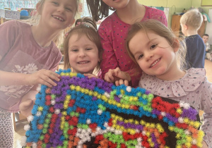 Dziewczynki prezentują obraz zrobiony z rzepów.