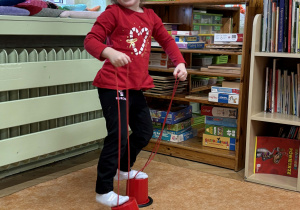 Dziewczynka chodzi na szczudłach.