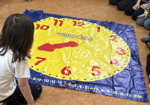 Dzieci bawią się zegarem na podłodze.