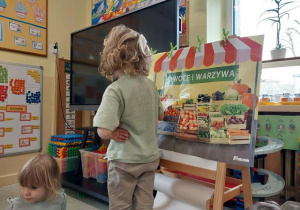 Chłopiec bawi się w zakupy w warzywniaku.