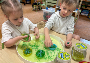 Dzieci bawią się zielonym slime.