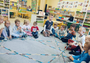 Dzieci wykorzystując kolorową włóczkę tworząc - pajęczynę przyjaźni.