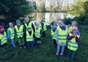 Dzieci obserwują przyrodę podczas spaceru nad staw.